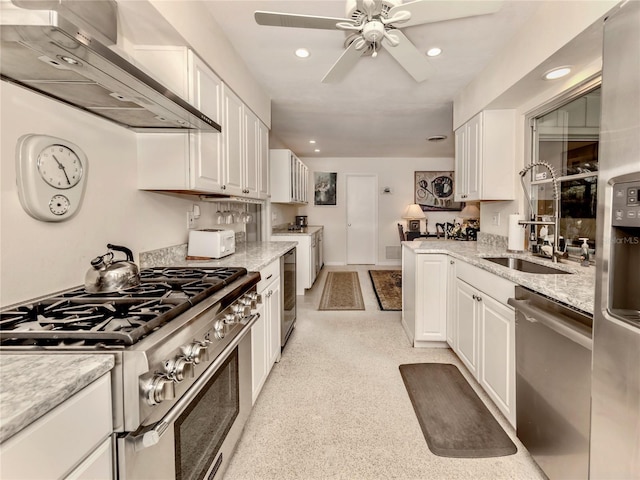 kitchen featuring appliances with stainless steel finishes, wall chimney range hood, light stone counters, and white cabinetry