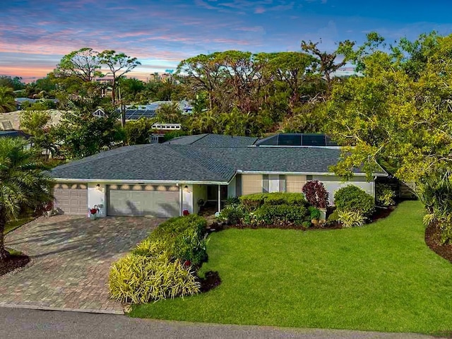 ranch-style house with a garage and a yard