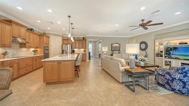 kitchen with appliances with stainless steel finishes, decorative light fixtures, an island with sink, a breakfast bar area, and crown molding