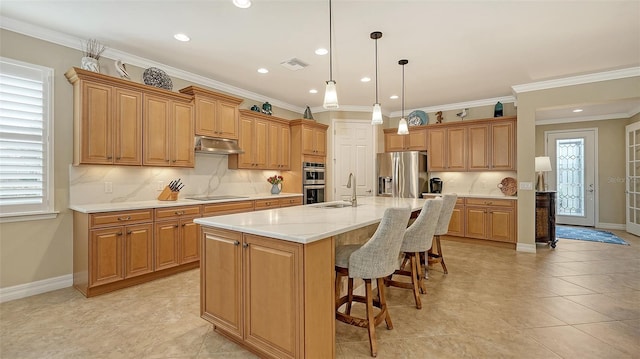 kitchen featuring appliances with stainless steel finishes, a kitchen island with sink, sink, and backsplash