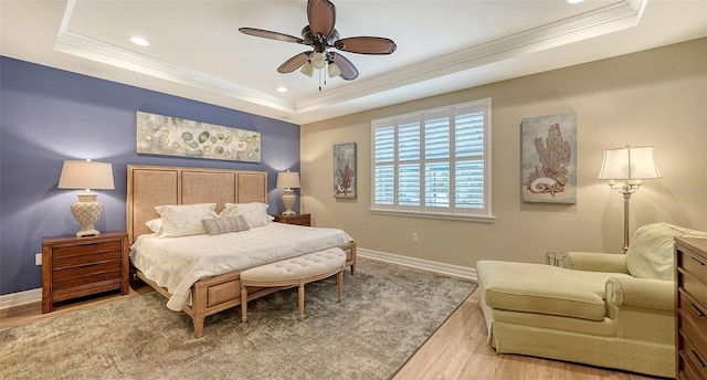 bedroom with light hardwood / wood-style floors, a raised ceiling, and ceiling fan