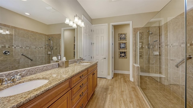 bathroom featuring vanity, wood-type flooring, and tiled shower