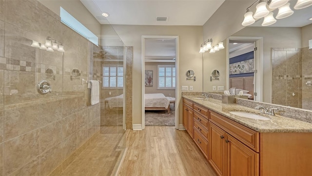 bathroom featuring hardwood / wood-style flooring, vanity, and a tile shower