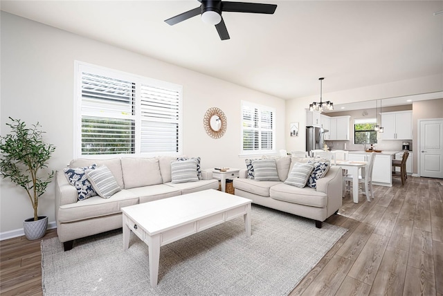 living room featuring ceiling fan with notable chandelier and light hardwood / wood-style floors