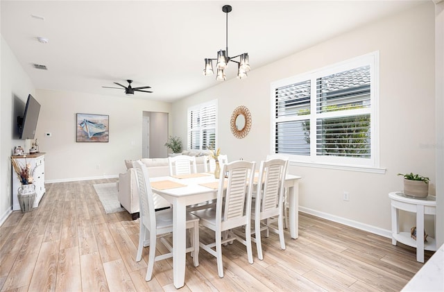 dining space featuring ceiling fan with notable chandelier and light hardwood / wood-style flooring