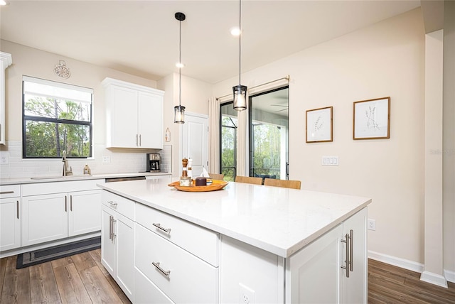 kitchen with sink, white cabinetry, hanging light fixtures, a center island, and decorative backsplash