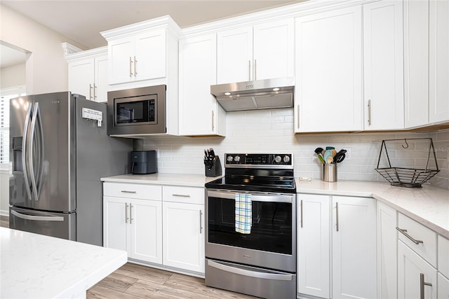 kitchen featuring white cabinetry, stainless steel appliances, light stone counters, and tasteful backsplash