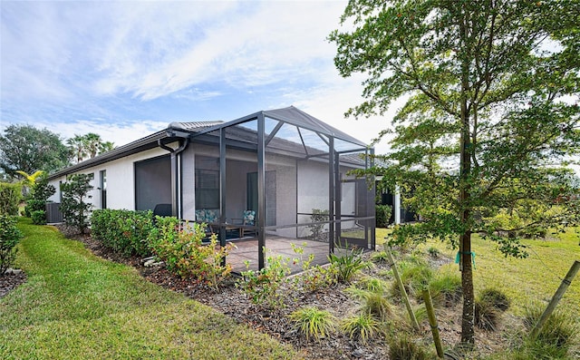 back of property with a lanai, a lawn, and a patio