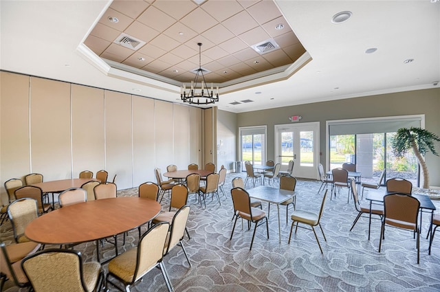 dining room with carpet floors, a chandelier, a raised ceiling, crown molding, and french doors