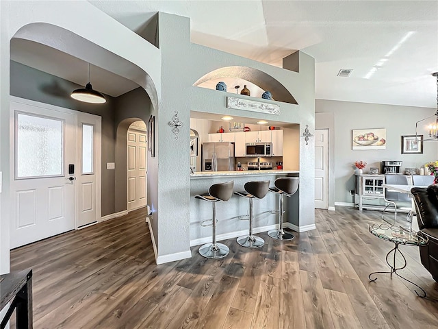 kitchen featuring white cabinetry, decorative light fixtures, vaulted ceiling, and appliances with stainless steel finishes