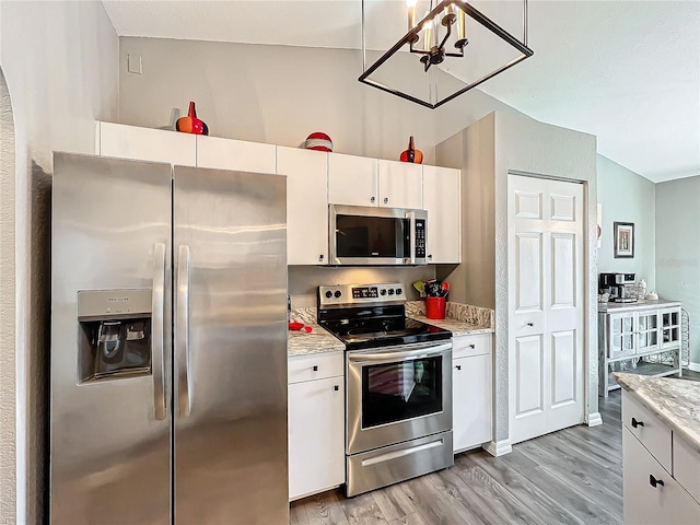 kitchen with stainless steel appliances, light stone counters, white cabinets, and light hardwood / wood-style floors