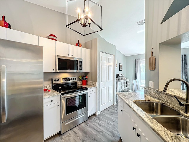 kitchen featuring appliances with stainless steel finishes, decorative light fixtures, sink, and white cabinets