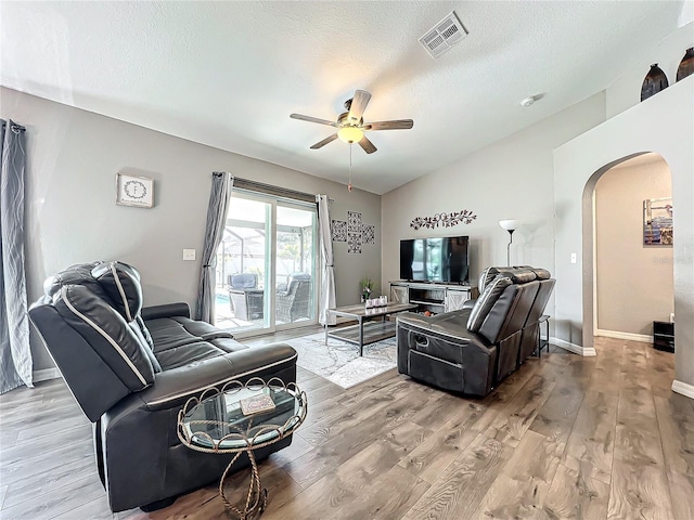 living room with lofted ceiling, ceiling fan, hardwood / wood-style flooring, and a textured ceiling