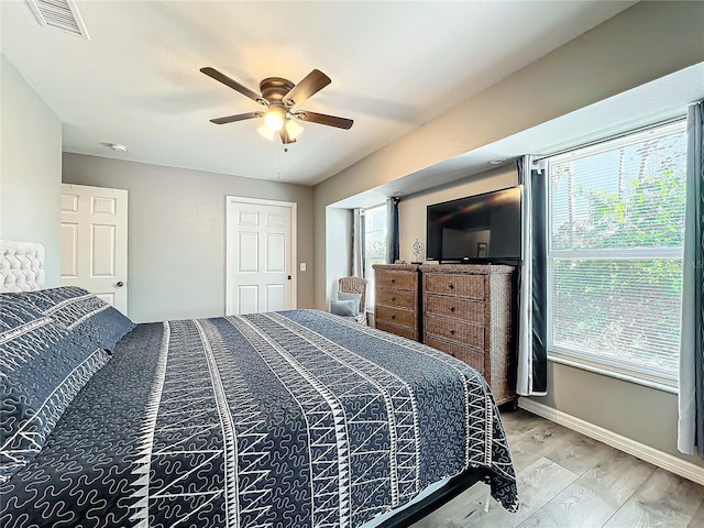 bedroom with hardwood / wood-style flooring, ceiling fan, and multiple windows