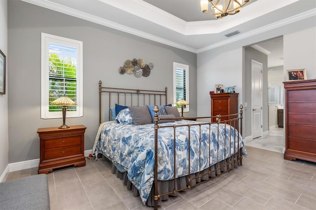 bedroom featuring a tray ceiling, ensuite bathroom, ornamental molding, and an inviting chandelier