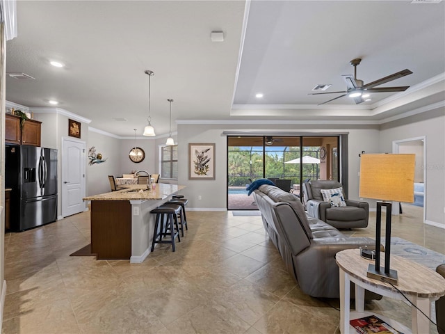 living room featuring ceiling fan, ornamental molding, a tray ceiling, and sink