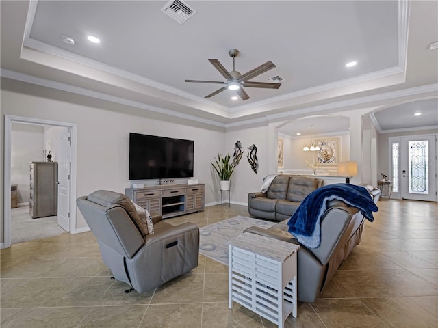 tiled living room featuring ceiling fan with notable chandelier, ornamental molding, and a raised ceiling