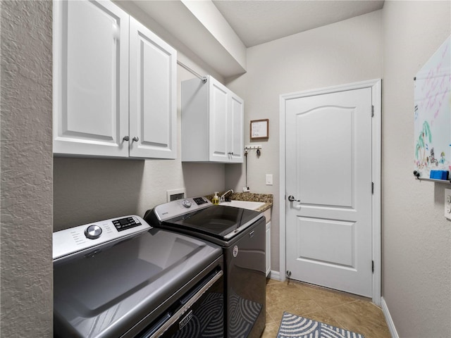 clothes washing area featuring washer and clothes dryer, sink, light tile patterned floors, and cabinets