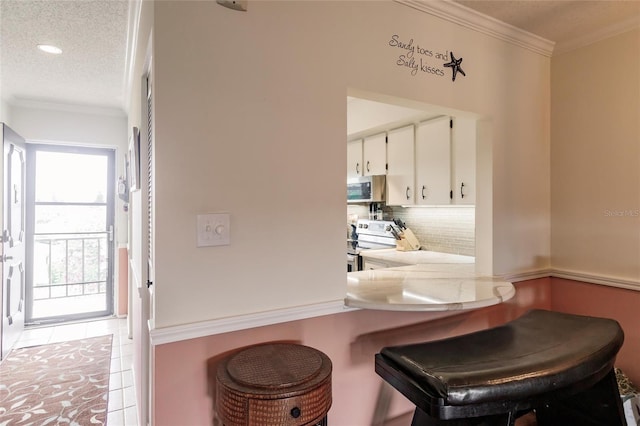 interior space with light tile patterned floors, white cabinetry, kitchen peninsula, appliances with stainless steel finishes, and decorative backsplash