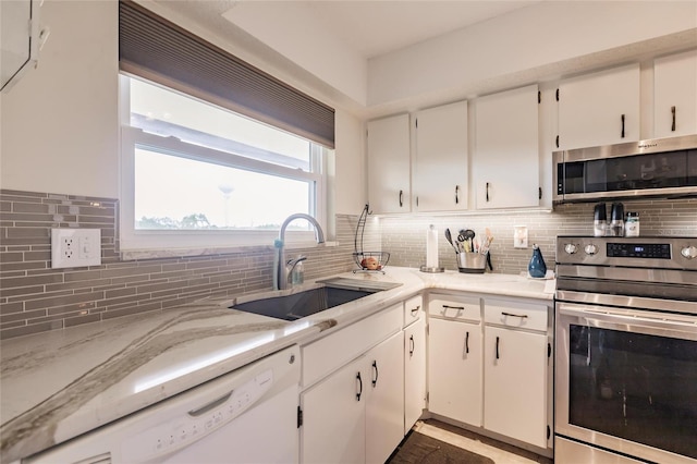 kitchen featuring sink, white cabinetry, backsplash, and stainless steel appliances