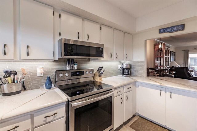 kitchen with white cabinets, decorative backsplash, light stone countertops, and stainless steel appliances