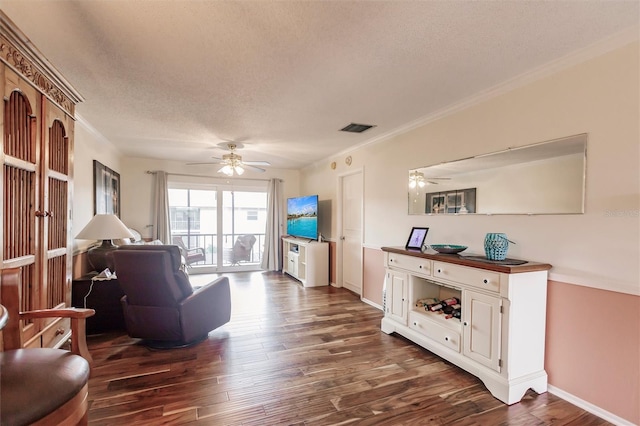 living room featuring ceiling fan, dark wood-type flooring, a textured ceiling, and ornamental molding