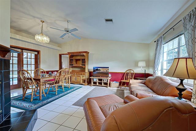 tiled living room featuring ceiling fan with notable chandelier and lofted ceiling