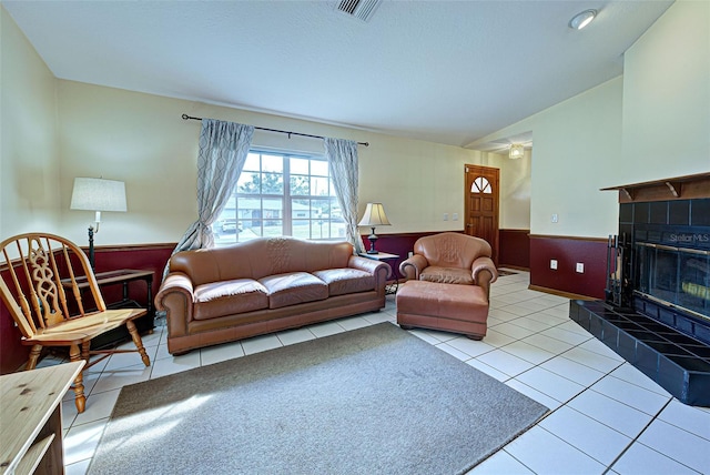 tiled living room with vaulted ceiling and a fireplace