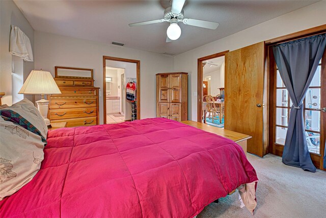 bedroom with light colored carpet, ensuite bath, and ceiling fan