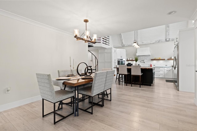 dining room featuring ornamental molding, a notable chandelier, and light hardwood / wood-style flooring