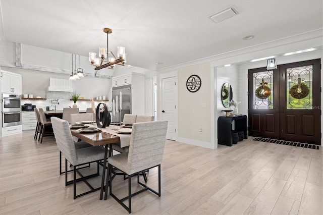 dining space with sink, a chandelier, and light hardwood / wood-style floors