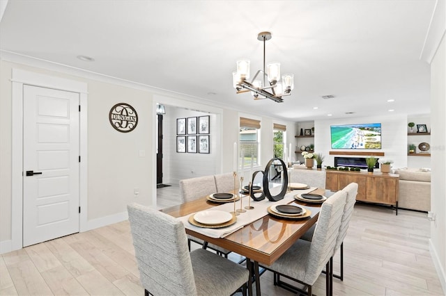 dining room featuring ornamental molding, a chandelier, and light wood-type flooring