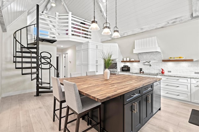 kitchen with a kitchen island, a breakfast bar, high vaulted ceiling, white cabinets, and hanging light fixtures