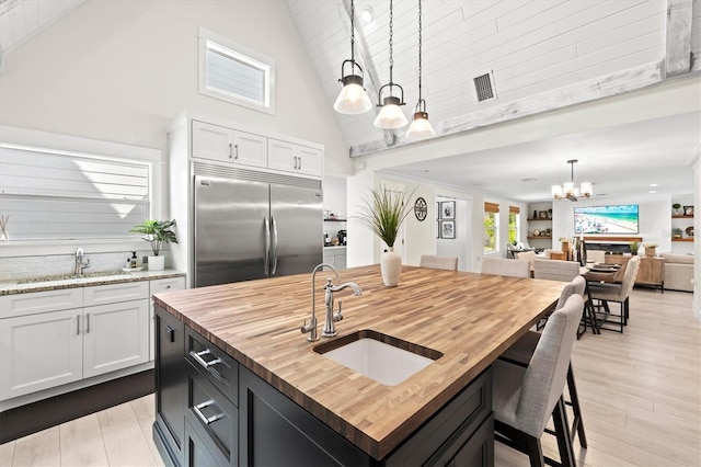 kitchen with hanging light fixtures, white cabinetry, and stainless steel built in fridge