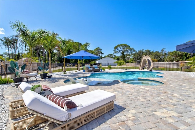 view of pool featuring an in ground hot tub, a water slide, and a patio area