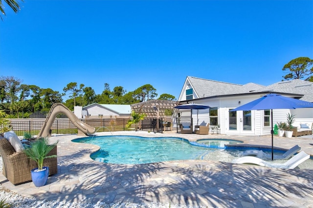 view of pool featuring a water slide, a patio, and an in ground hot tub