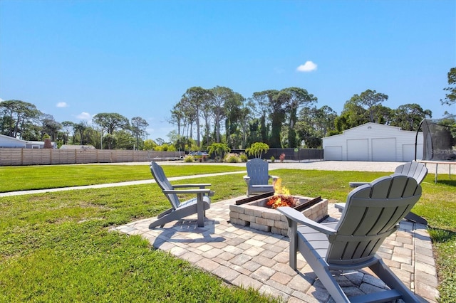 view of yard with a trampoline, a patio, an outdoor fire pit, a garage, and an outdoor structure