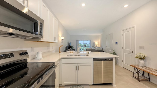 kitchen featuring sink, light tile patterned floors, appliances with stainless steel finishes, white cabinetry, and kitchen peninsula