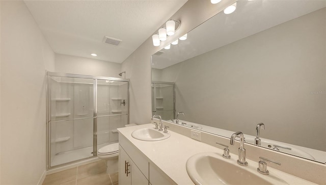 bathroom featuring tile patterned flooring, vanity, a shower with shower door, and toilet