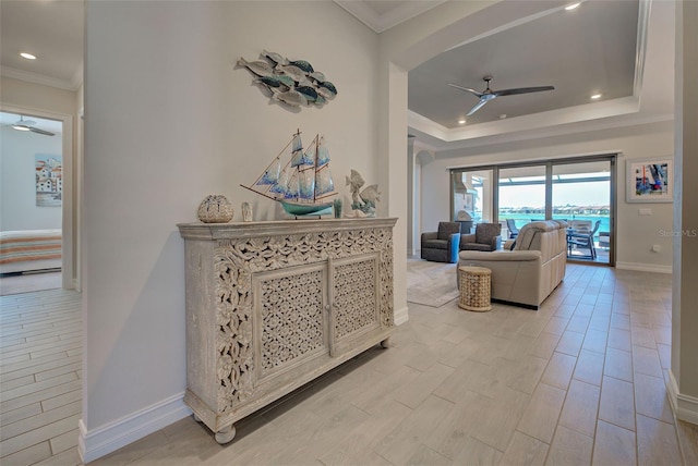 living room featuring a tray ceiling, ornamental molding, and ceiling fan