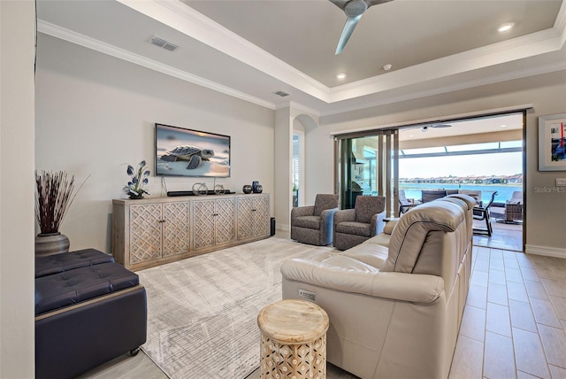 living room featuring crown molding, ceiling fan, and a raised ceiling