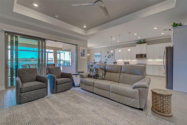 living room with crown molding, ceiling fan, and a tray ceiling