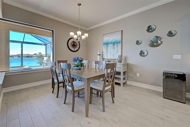 dining room with a water view, ornamental molding, an inviting chandelier, and light wood-type flooring