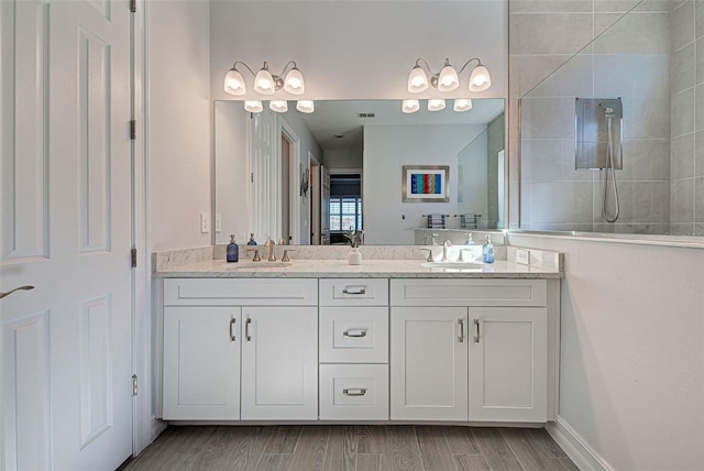 bathroom featuring vanity, hardwood / wood-style flooring, and tiled shower