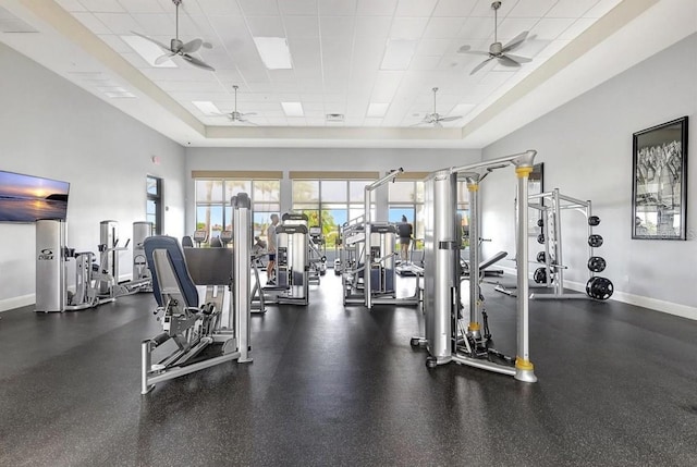 exercise room with ceiling fan, a tray ceiling, and a drop ceiling