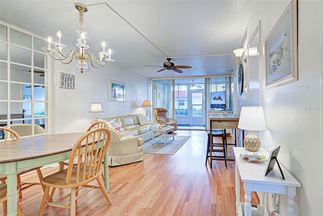 living room with ceiling fan with notable chandelier and hardwood / wood-style floors