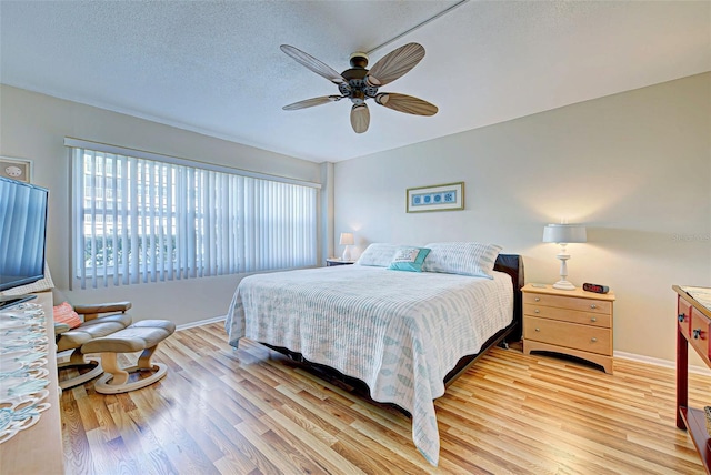 bedroom featuring ceiling fan, a textured ceiling, and light hardwood / wood-style floors