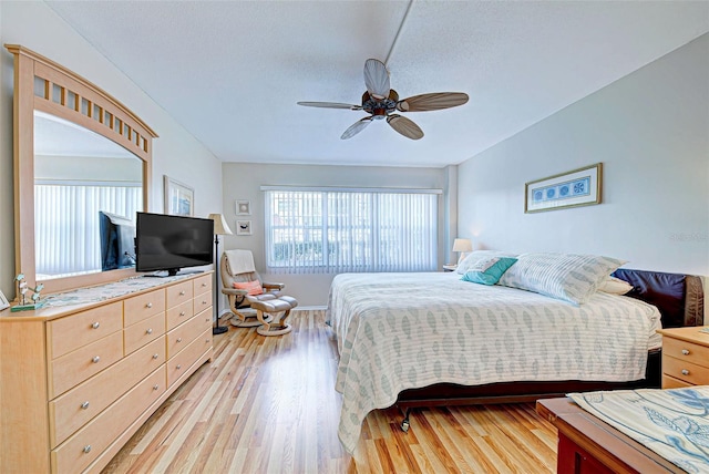 bedroom featuring light wood-type flooring, ceiling fan, and a textured ceiling