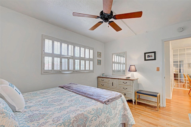 bedroom featuring a textured ceiling, ceiling fan, and light hardwood / wood-style flooring