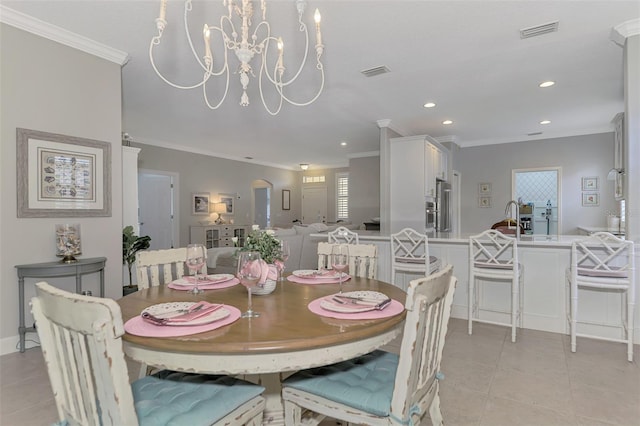 tiled dining room featuring sink, ornamental molding, and an inviting chandelier